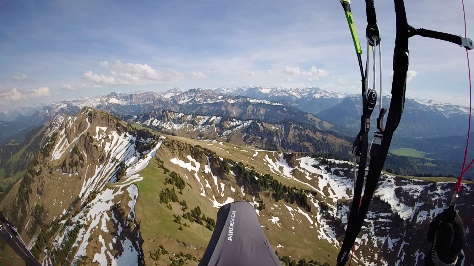 Uitzicht vanuit een paraglider boven een bergkam met sneeuwvelden