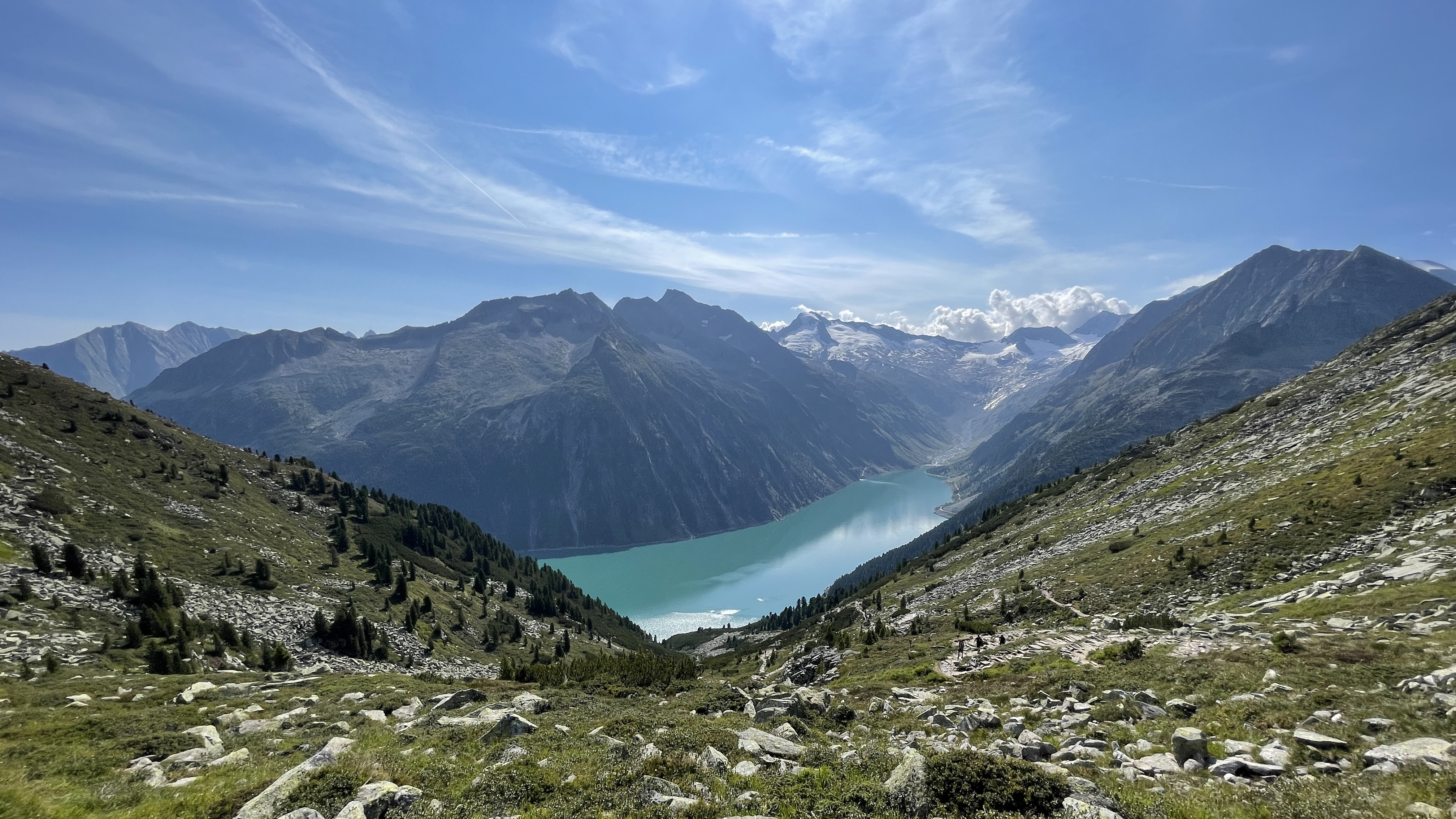 Een pad met uitzicht op een turquoise meer tussen hoge bergen